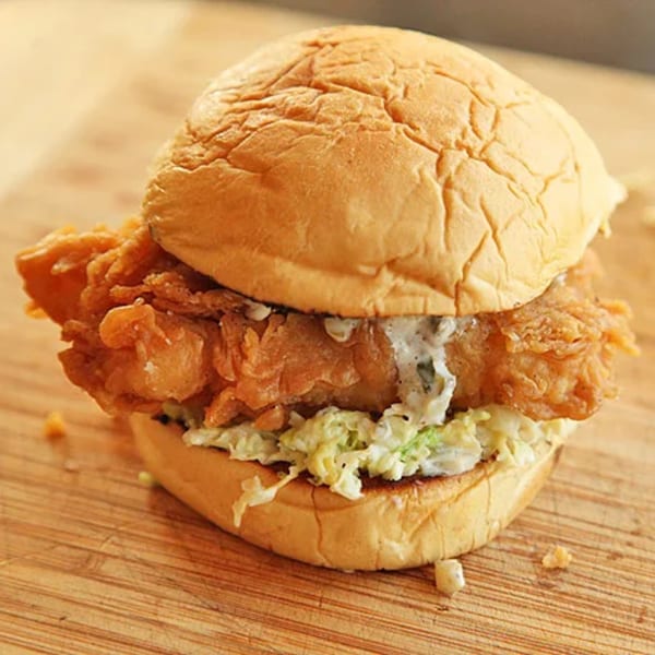 A crispy fried fish sandwich with coleslaw and tartar sauce on a bun, from Jammin Island BBQ.
